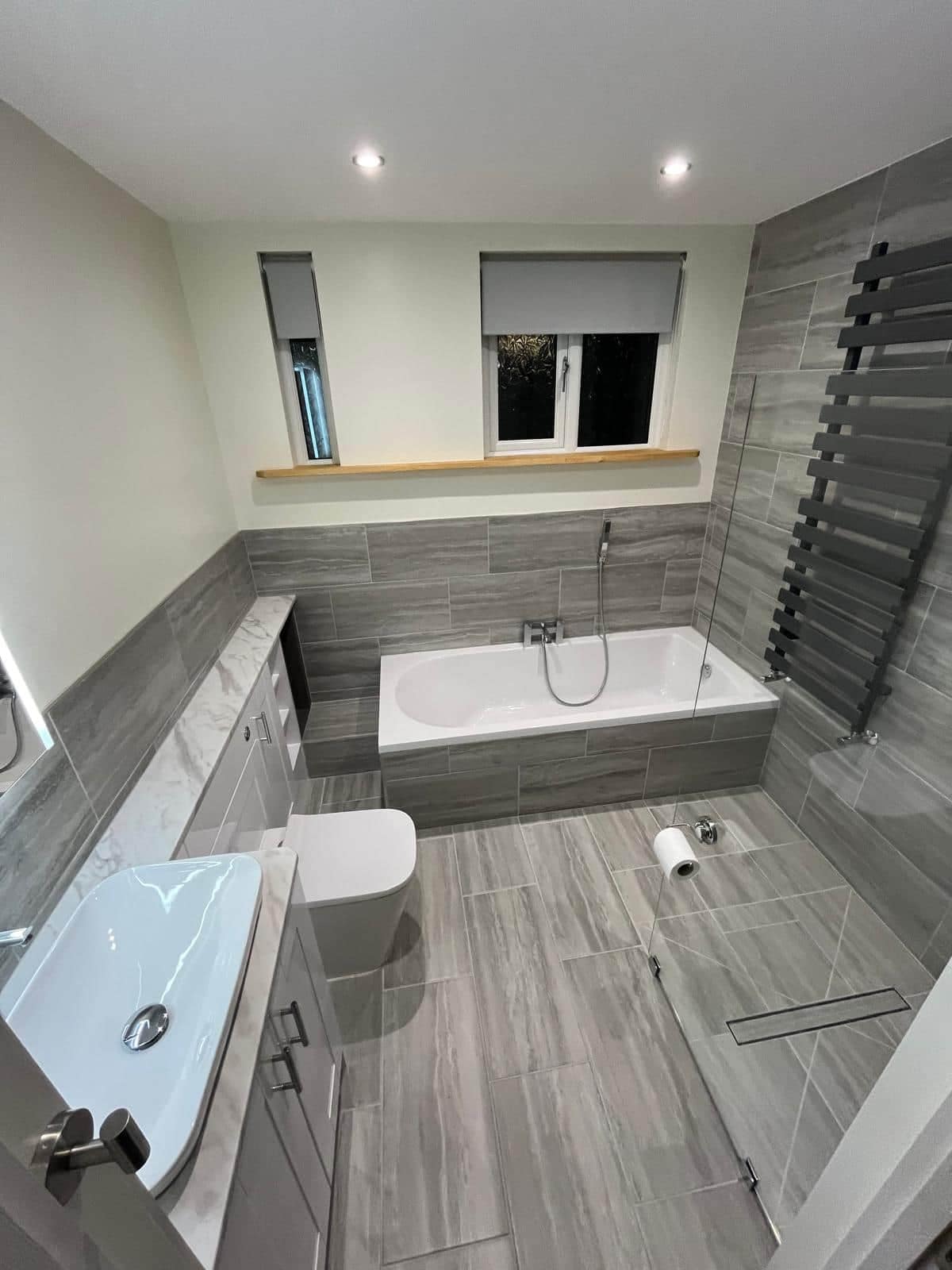 Home Wet room with bathtub, toilet, vanity, radiator and grey tiled walls
