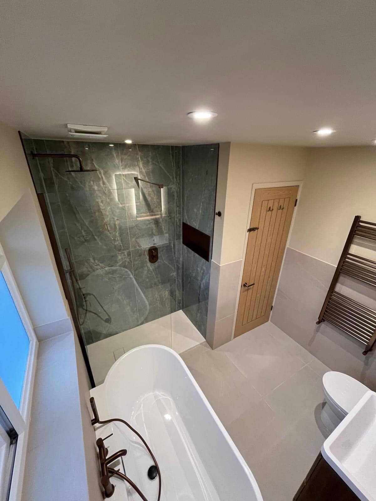 Home Refurbished bathroom in Gloucester with freestanding bathtub, walk-in shower, blue-grey marble-effect wall tiles and heated towel radiator