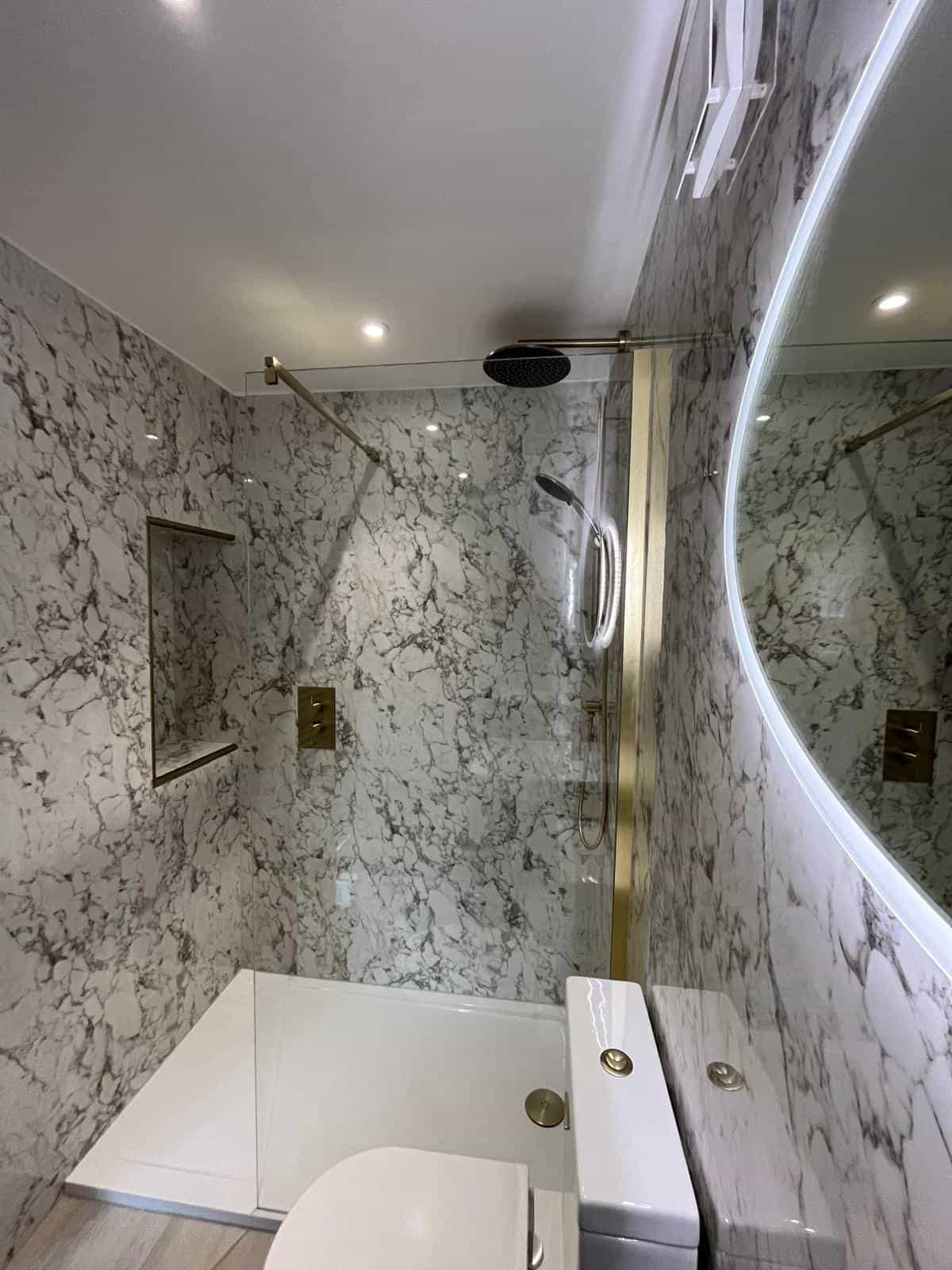 Home Completed ensuite bathroom in Tuffley with marble-effect wall panels, walk-in shower, recessed shelf and brushed brass fittings