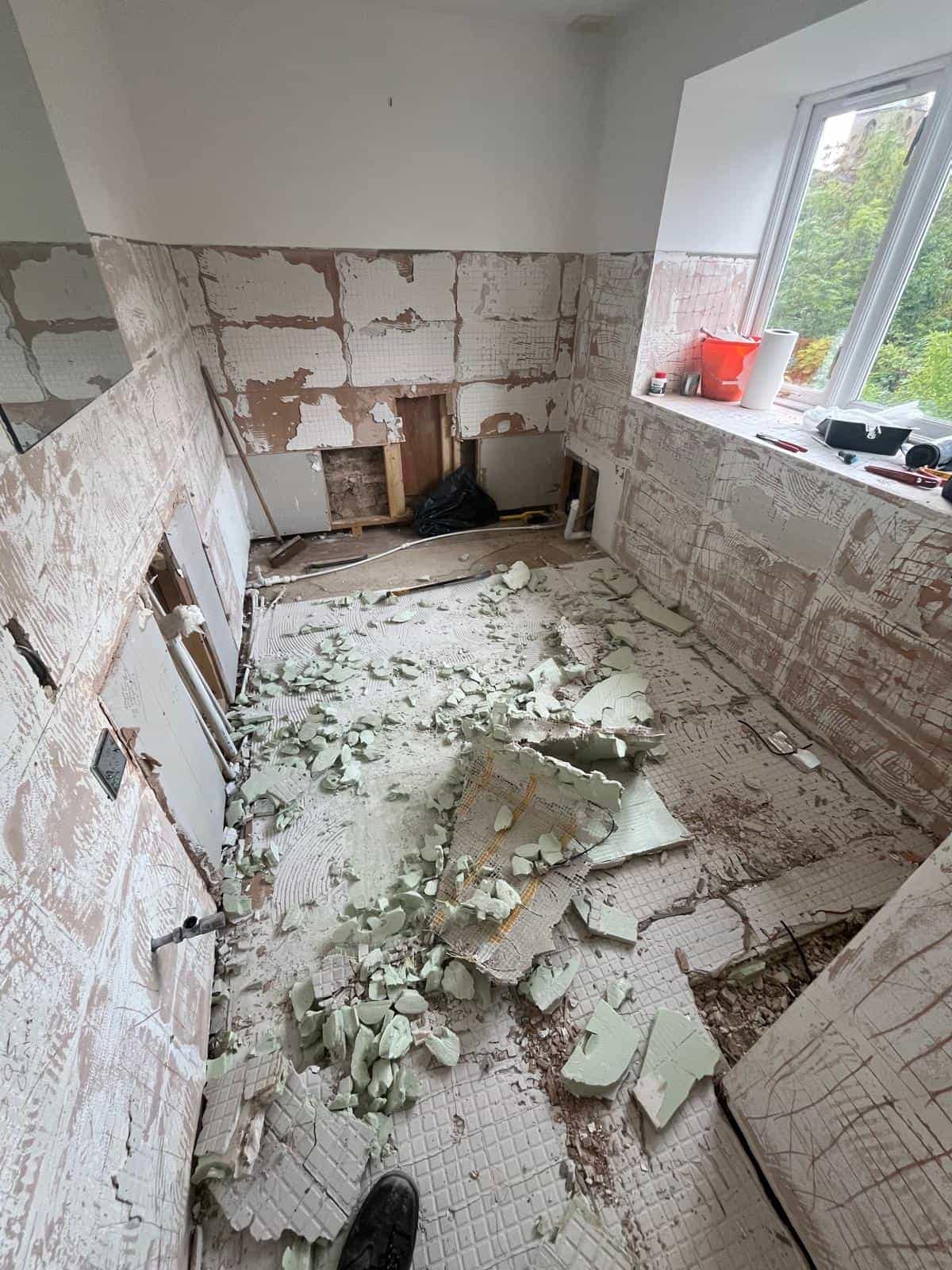 Home Large bathroom renovation in Minchinhampton showing stripped wall surfaces, exposed floor and broken tiles following removal of the old fittings